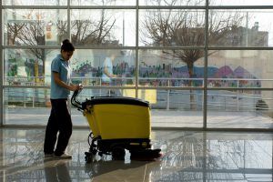 A janitor operating a floor cleaning machine in the lobby of a school in New York City. These floor cleaning machines can also be used for office cleaning services.